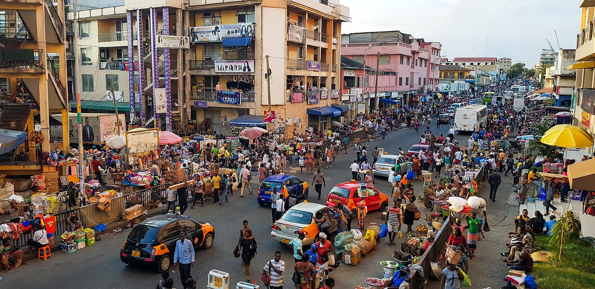 Busy commercial street in Accra Central with taxis, shoppers and roadside traders