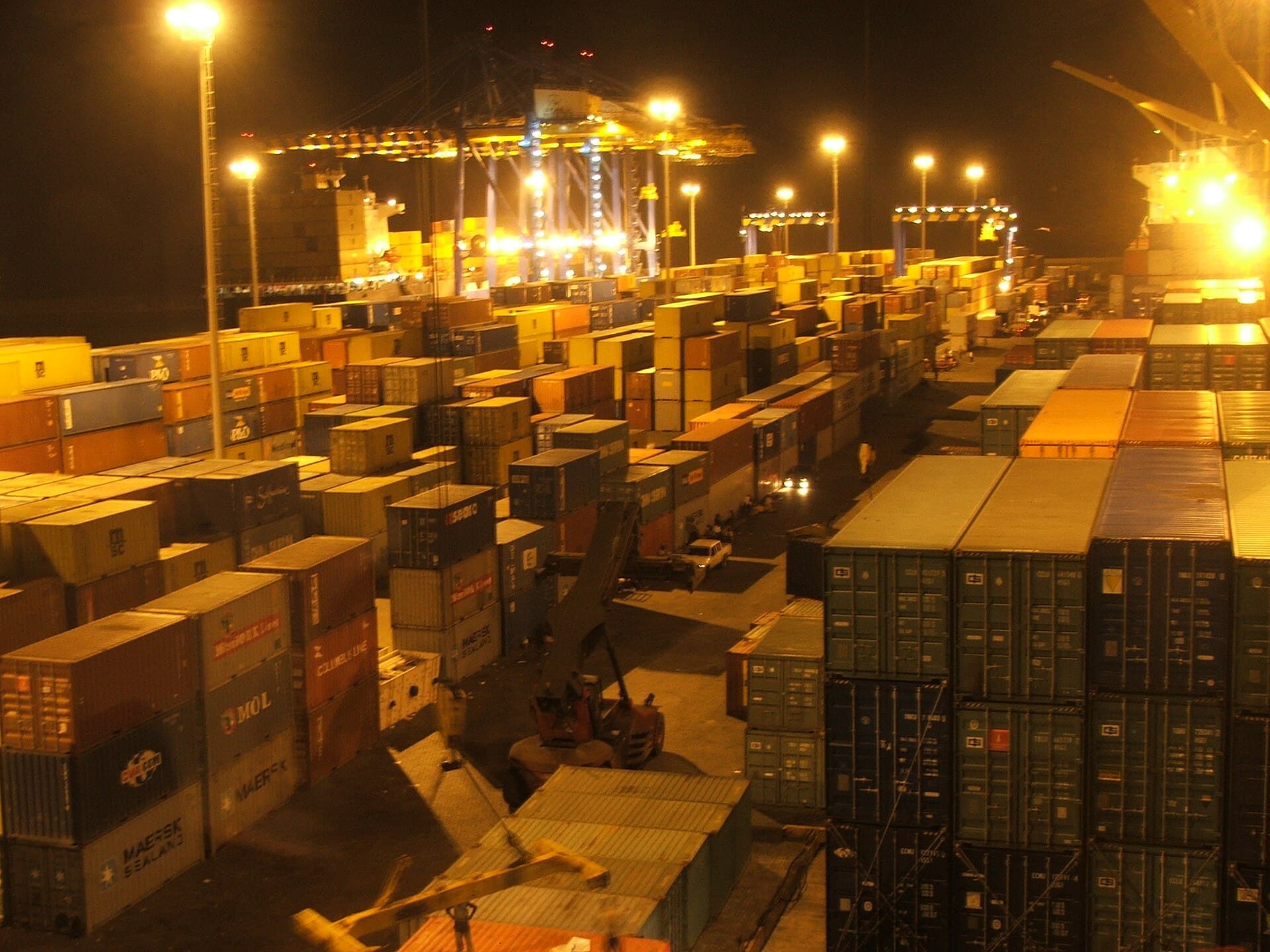Shipping containers stacked under floodlights at the Tema port container terminal at night